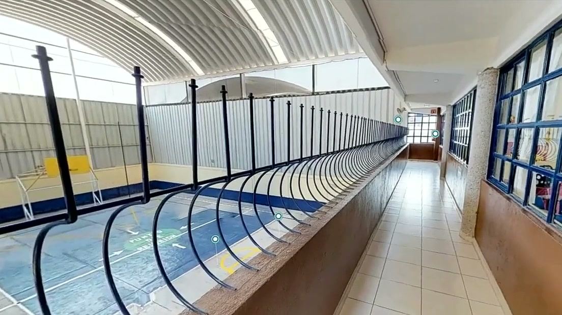 Pasillo del piso superior con barandal de líneas curvas y techo en arco, con vista al patio.